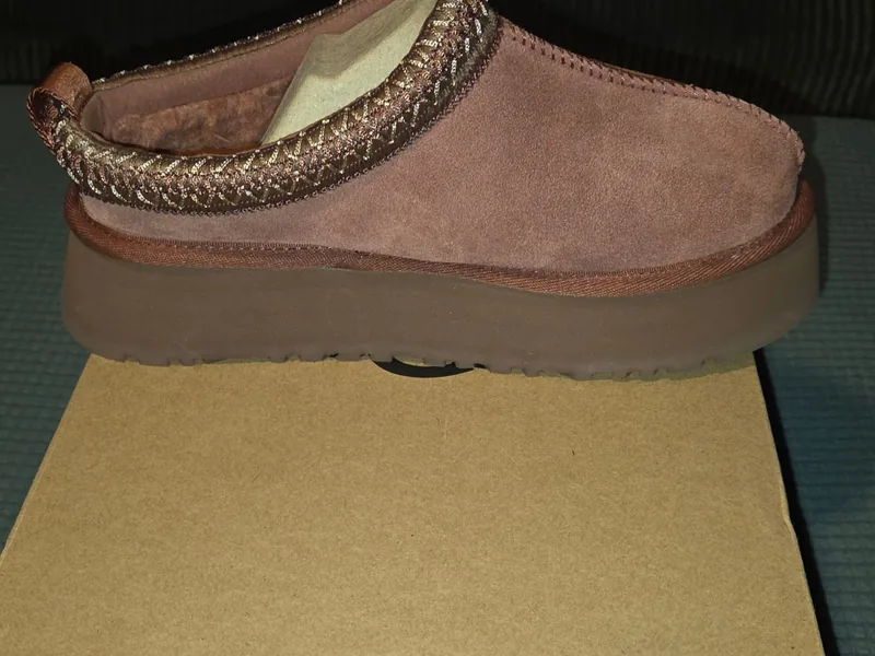UGG Tazz platform slipper in Red Jasper suede, side profile with the braided collar, standing on its box